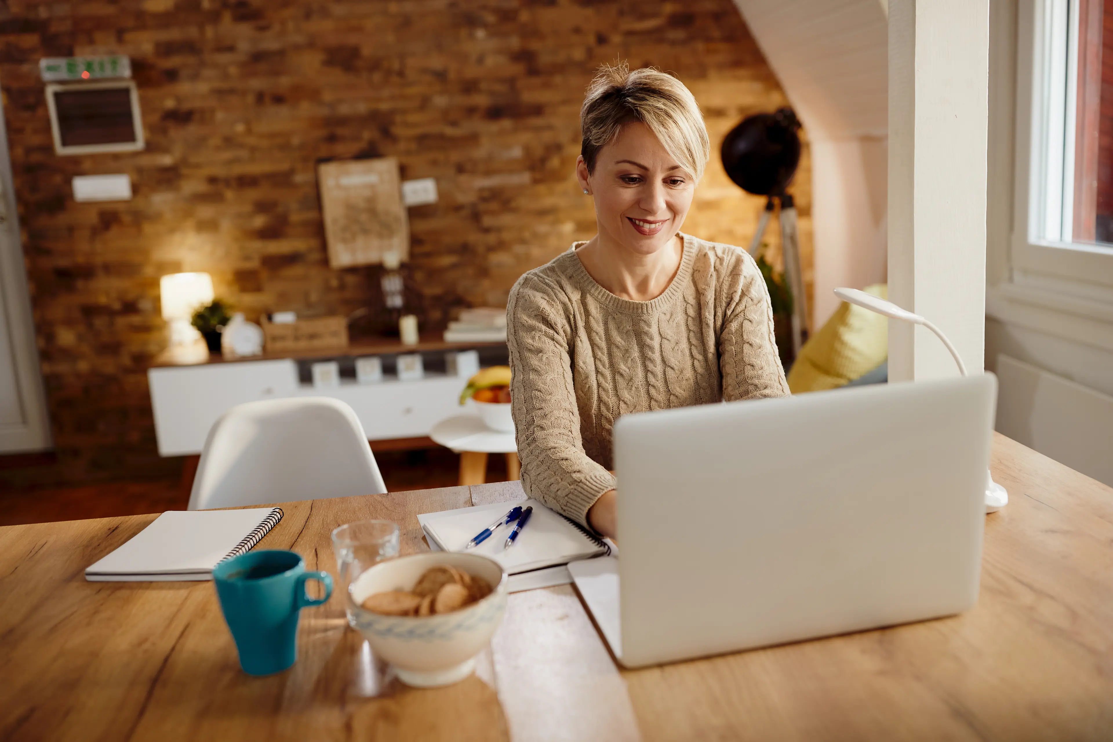 Gründerin arbeitet entspannt am Laptop im Home-Office mit Kaffee – persönliche Geschäftsadresse von Firmenadresse.com